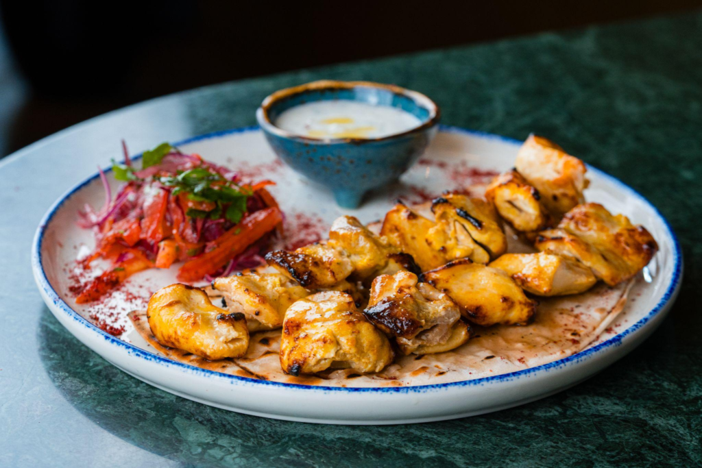 Juicy joojeh kebab served with grilled vegetables, yogurt dip at Le Flamant Rose in Dubai