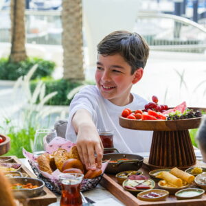 Young boy enjoying a family brunch with fresh bread, fruits, and Mediterranean breakfast dishes at a restaurant