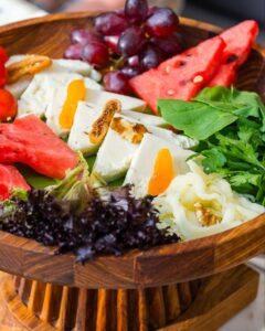 Colorful gluten-free fruit and cheese platter with watermelon, grapes, leafy greens, and nuts