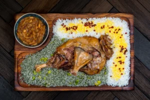 Traditional lamb mandi with saffron rice and curry bowl served on wooden platter
