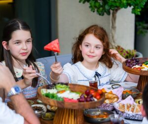 A joyful family enjoying a colorful Persian meal with fresh fruits and traditional dishes outdoors