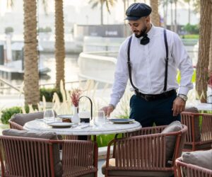 Waiter setting an outdoor dining table by the waterfront at Le Flamant Rose in Dubai Creek Harbour