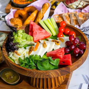 Colorful spread of traditional Iranian dishes featuring fresh fruits, vegetables, bread, and appetizers beautifully arranged on a dining table.